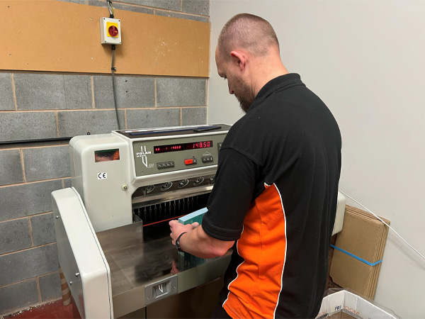 Team member Gary using a polar industrial guillotine for printed flyers.