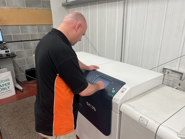 Team member peter configuring industral printing machine prior to producing printed posters.